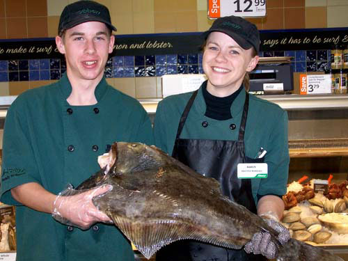 Acton Sobeys Seafood Department. Brandon and manager Karen hold up a large fish